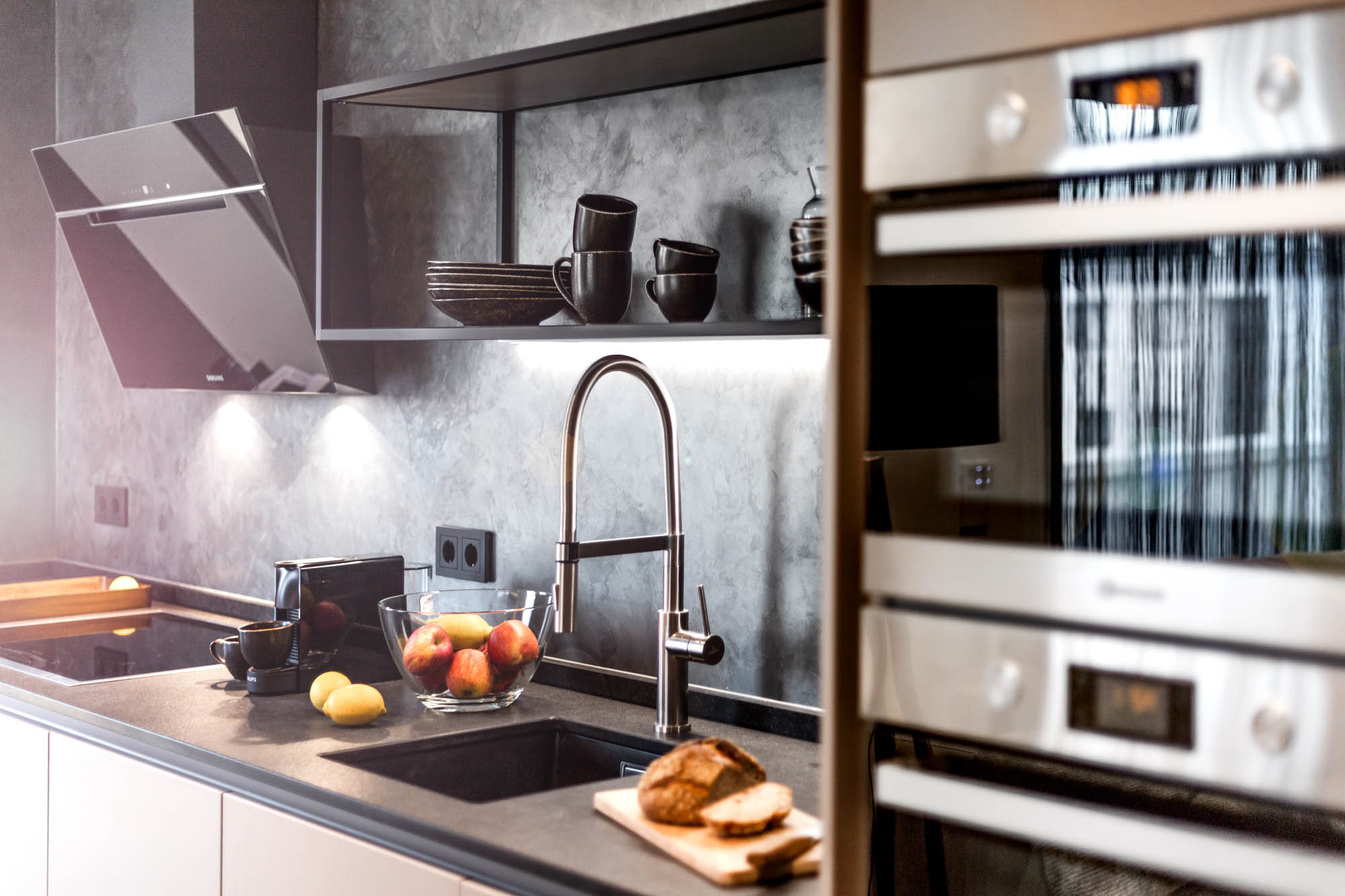 Die Küche des Primera Penthouse hat einen großen Arbeitsbereich und den neuesten Geräten ausgestattet. Das offene Regal und das Geschirr sind in dunklem braun gehalten.
