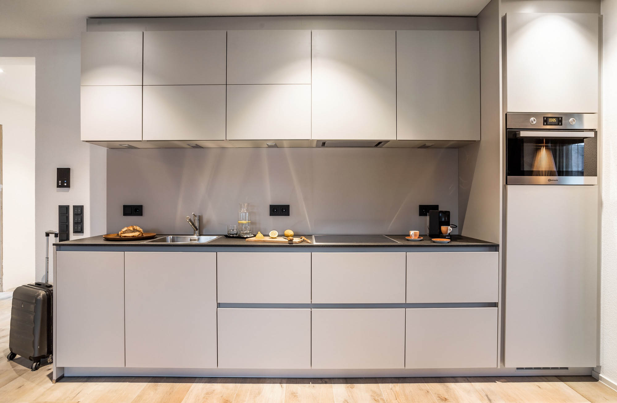 Die Küchenzeile in hellem Grau ist mit allen notwendigen Geräten und einer Kapsle-Kaffemaschine ausgestattet