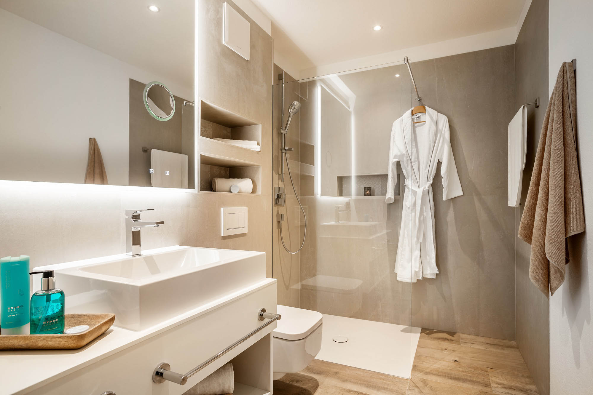 Das Badezimmer im Comfort Apartment ist helen grautönen und weiß gestaltet. die Dusche ist ebenerdig und behindertengerecht.